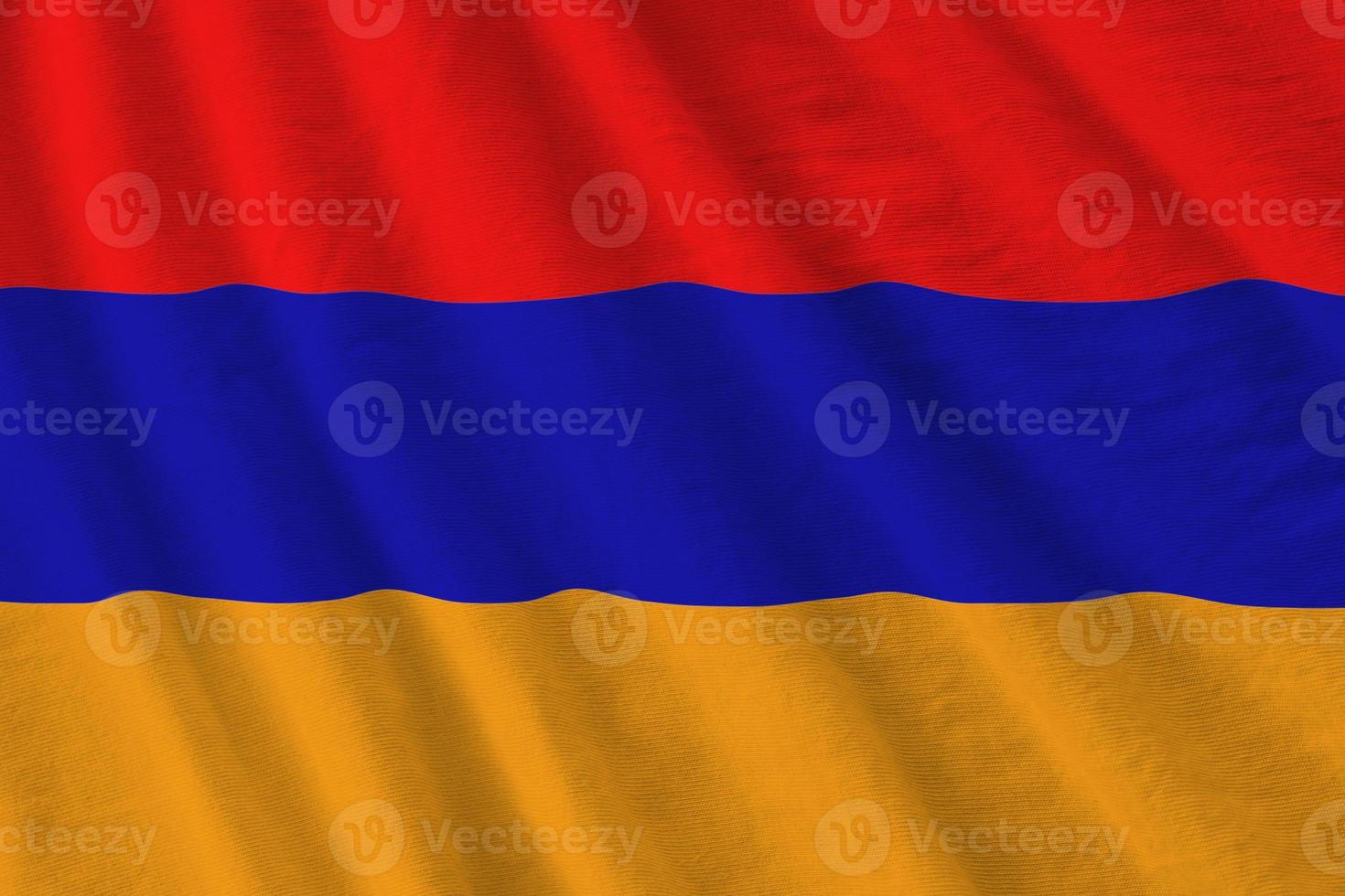 Armenia flag with big folds waving close up under the studio light indoors. The official symbols and colors in banner photo