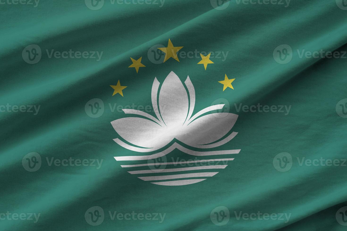 Macau flag with big folds waving close up under the studio light indoors. The official symbols and colors in banner photo