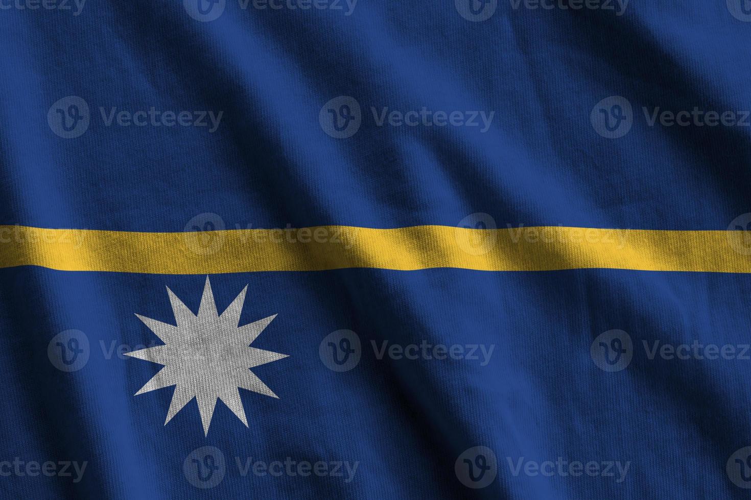 Nauru flag with big folds waving close up under the studio light indoors. The official symbols and colors in banner photo