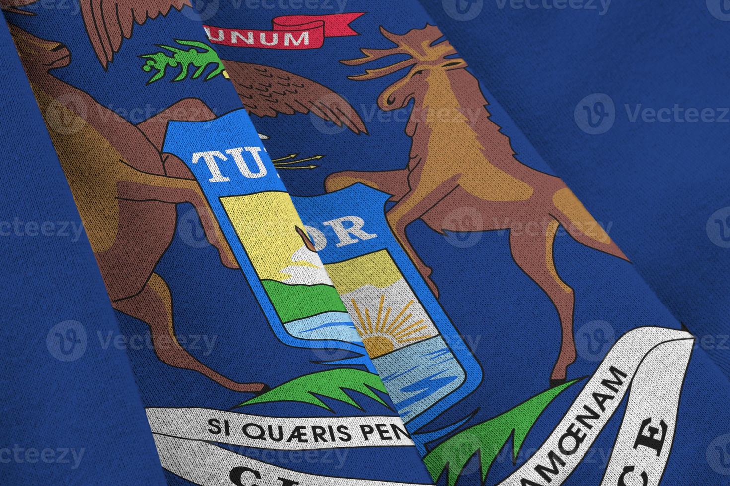 Michigan US state flag with big folds waving close up under the studio light indoors. The official symbols and colors in banner photo