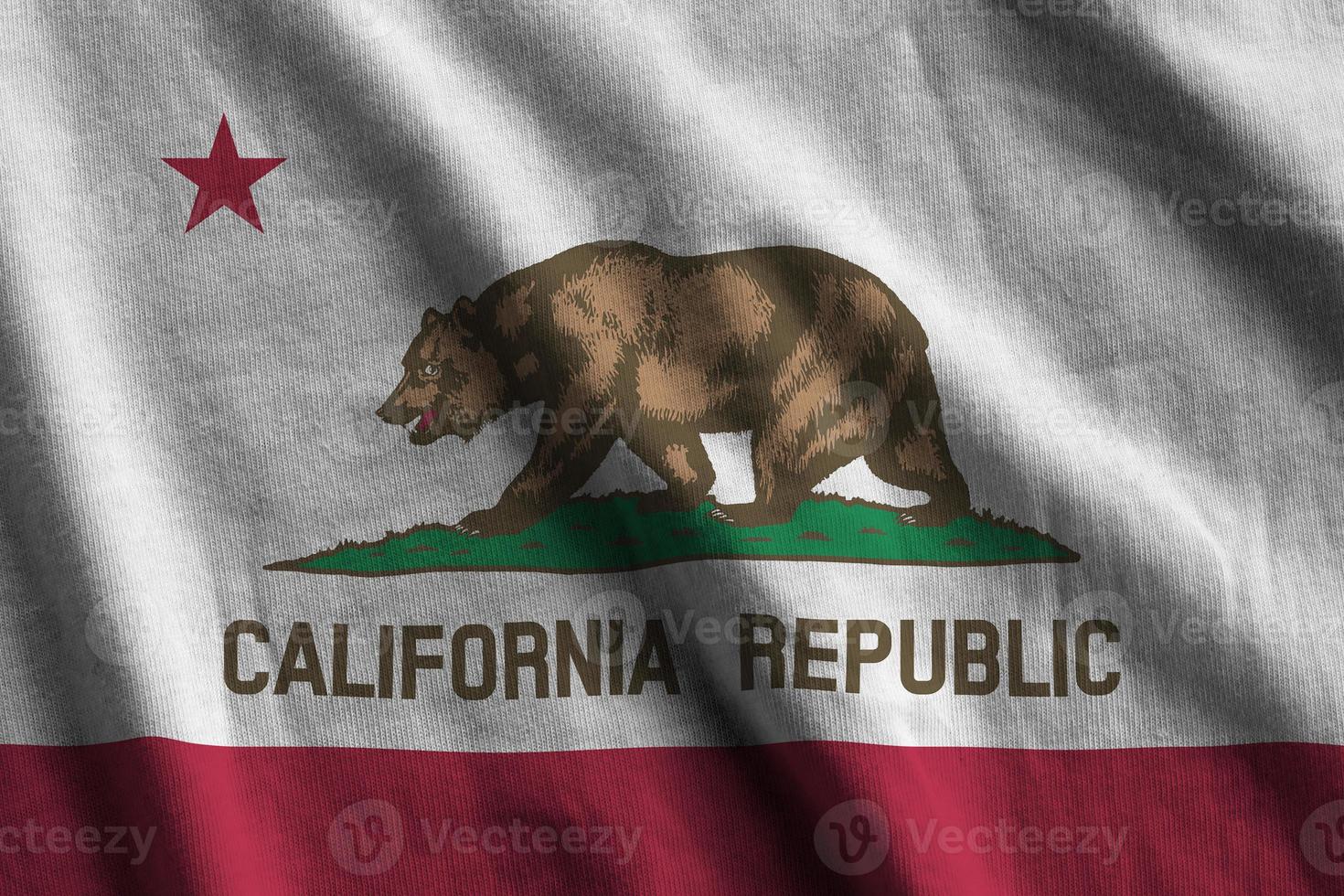 California US state flag with big folds waving close up under the studio light indoors. The official symbols and colors in banner photo