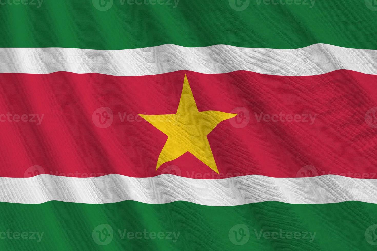Suriname flag with big folds waving close up under the studio light indoors. The official symbols and colors in banner photo