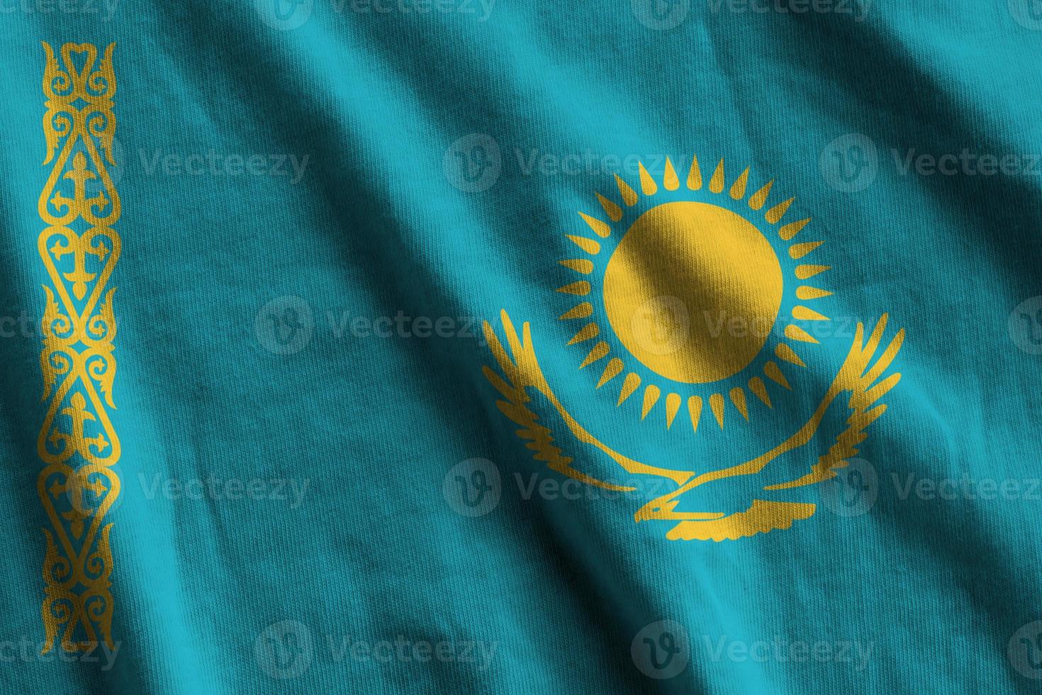 Kazakhstan flag with big folds waving close up under the studio light indoors. The official symbols and colors in banner photo