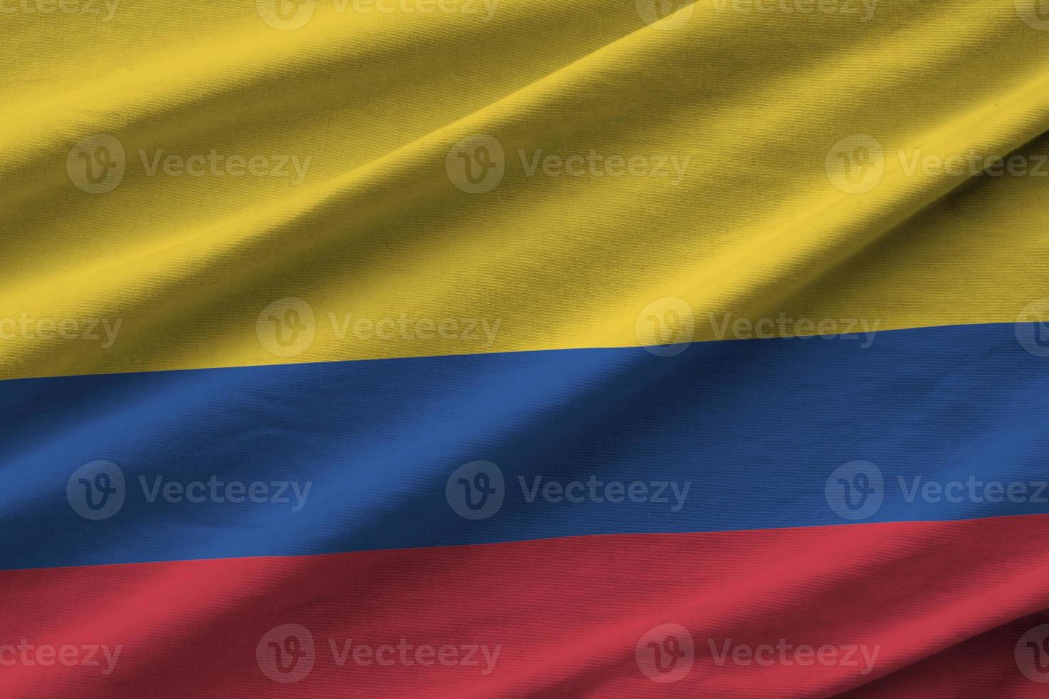 Colombia flag with big folds waving close up under the studio light indoors. The official symbols and colors in banner photo