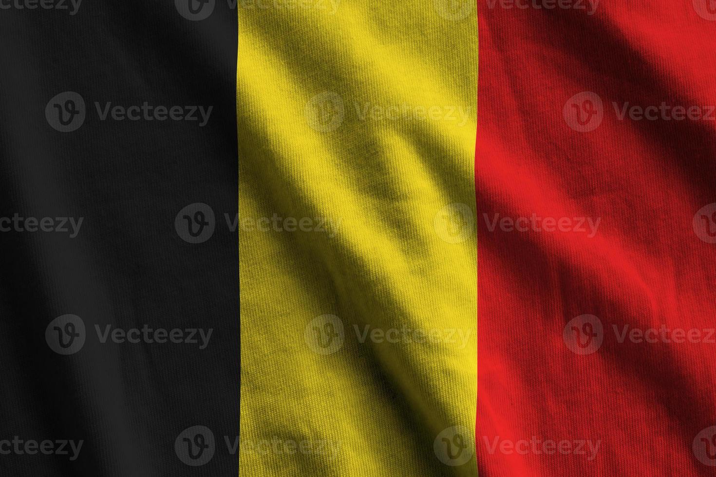 Belgium flag with big folds waving close up under the studio light indoors. The official symbols and colors in banner photo