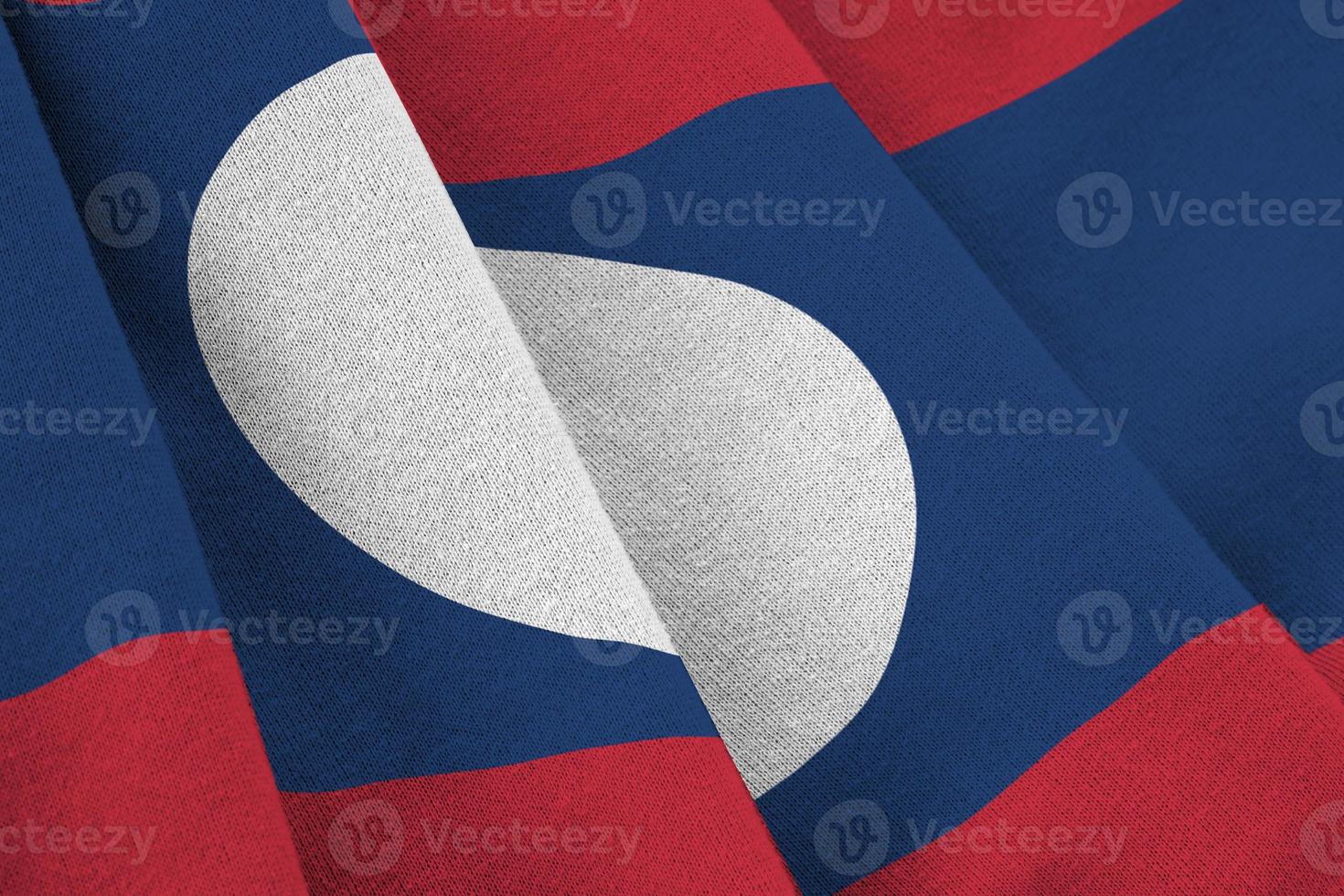 Laos flag with big folds waving close up under the studio light indoors. The official symbols and colors in banner photo