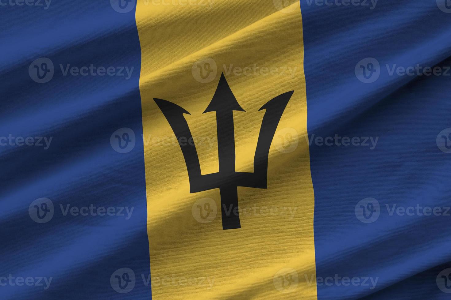 Barbados flag with big folds waving close up under the studio light indoors. The official symbols and colors in banner photo