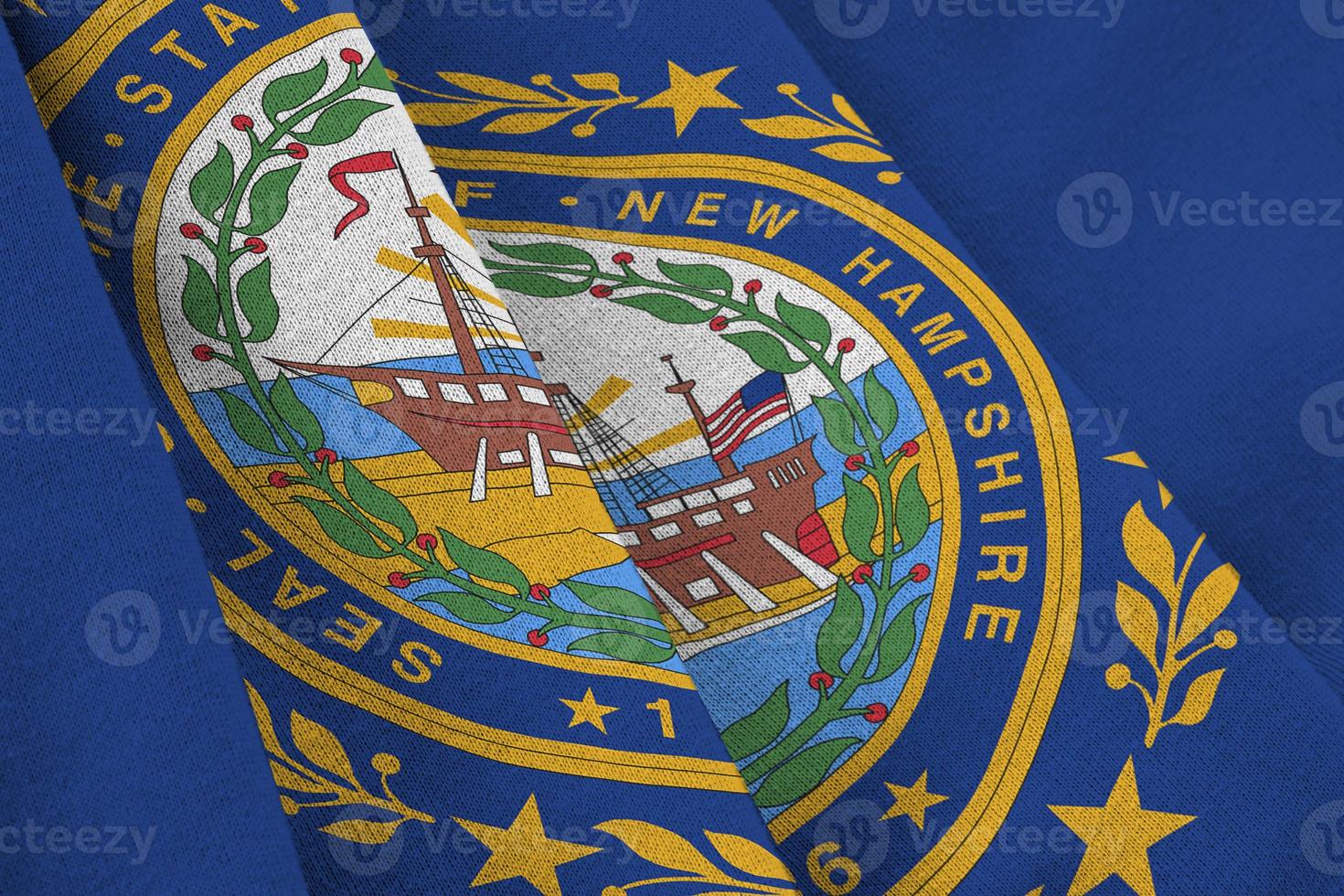 New Hampshire US state flag with big folds waving close up under the studio light indoors. The official symbols and colors in banner photo