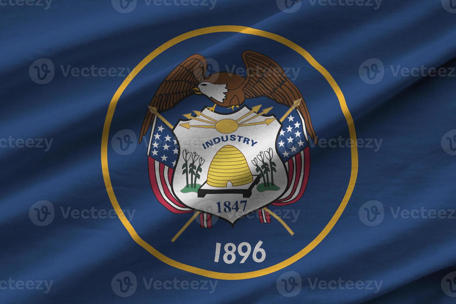 Utah US state flag with big folds waving close up under the studio light indoors. The official symbols and colors in banner photo