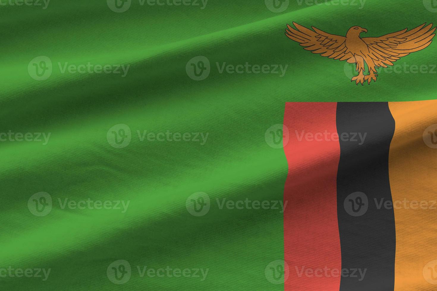 Zambia flag with big folds waving close up under the studio light indoors. The official symbols and colors in banner photo