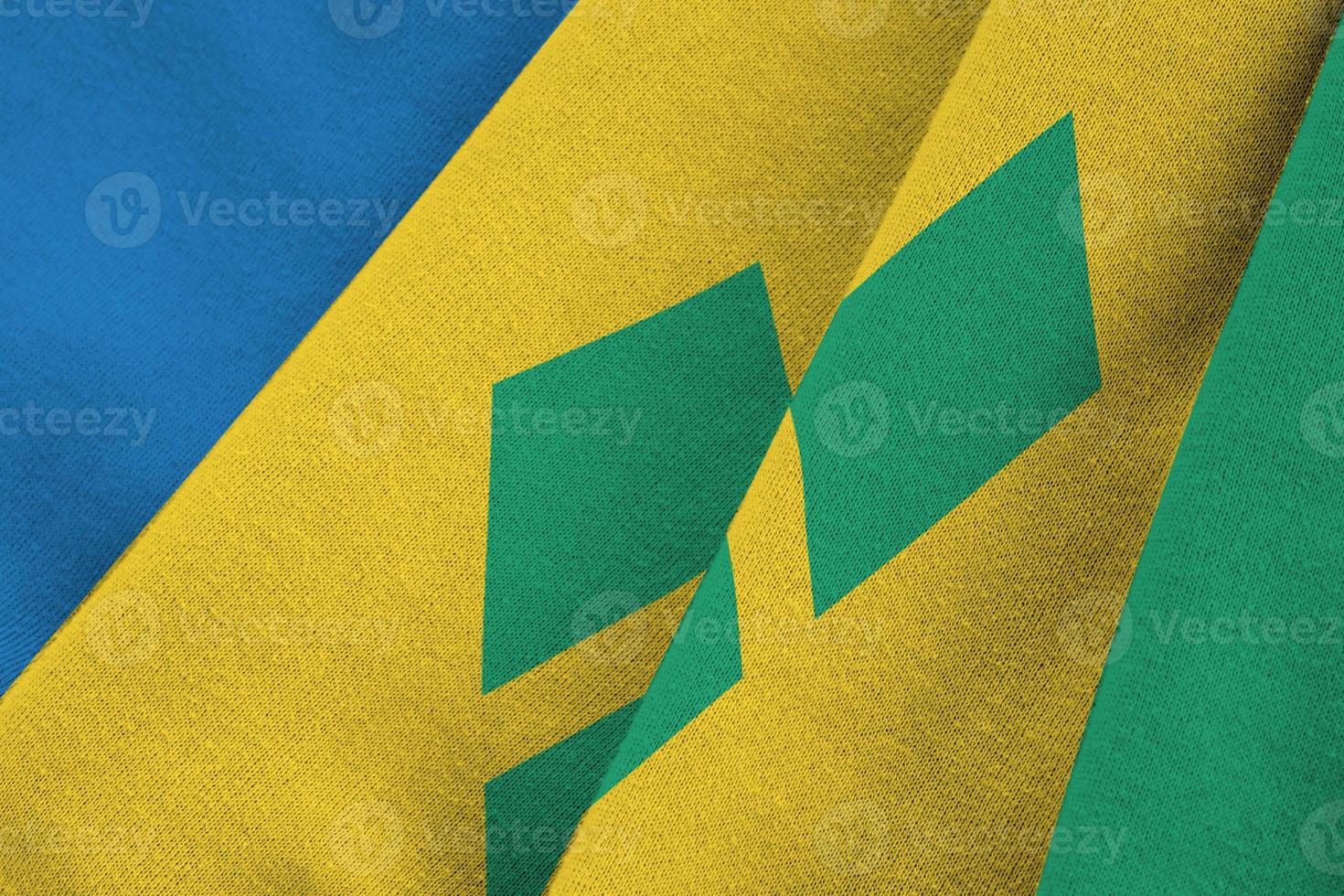Saint Vincent and the Grenadines flag with big folds waving close up under the studio light indoors. The official symbols and colors in banner photo