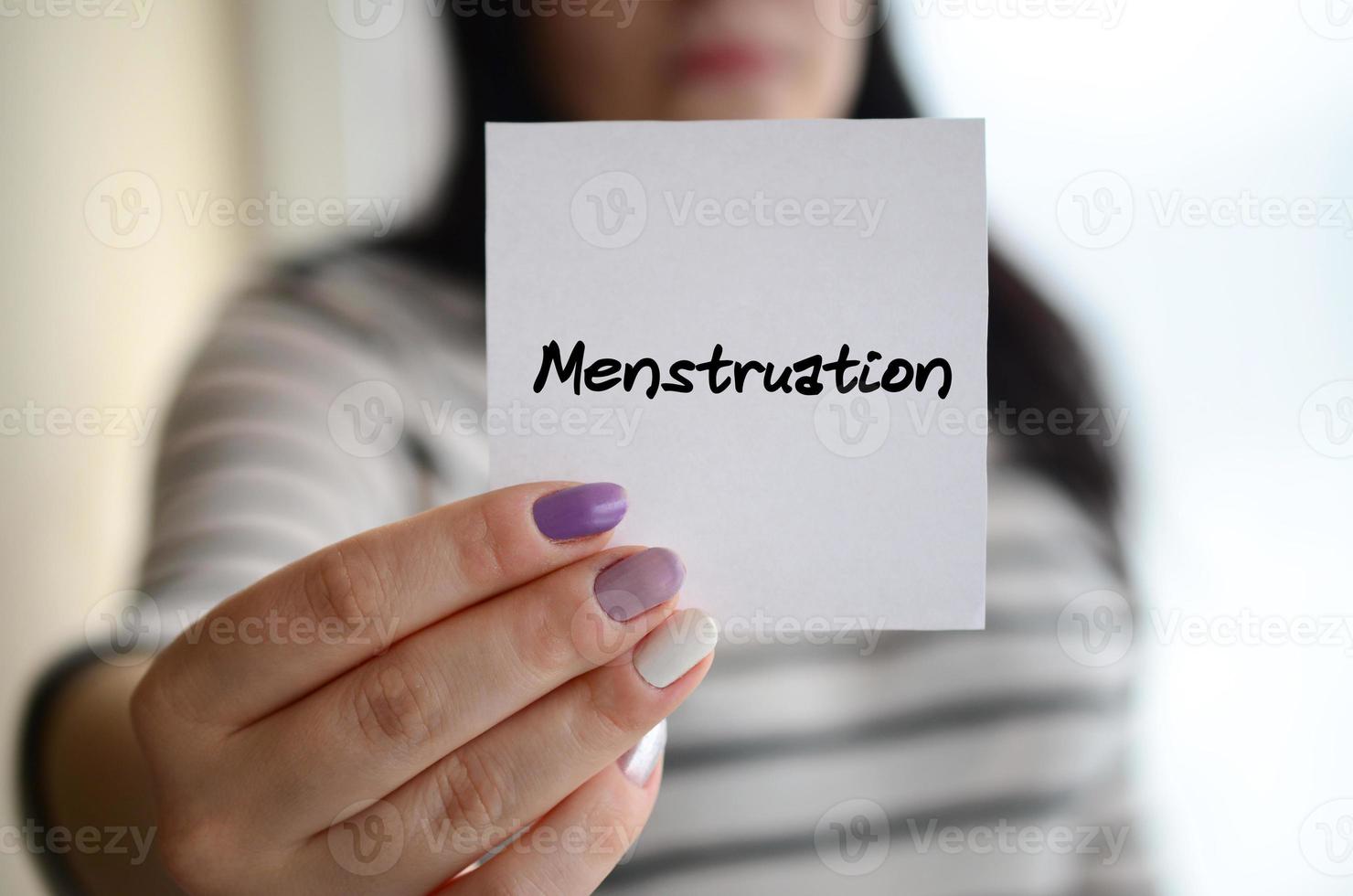 Young sad girl shows a white sticker. Caucasian brunette holding a sheet of paper with message. Menstruation photo