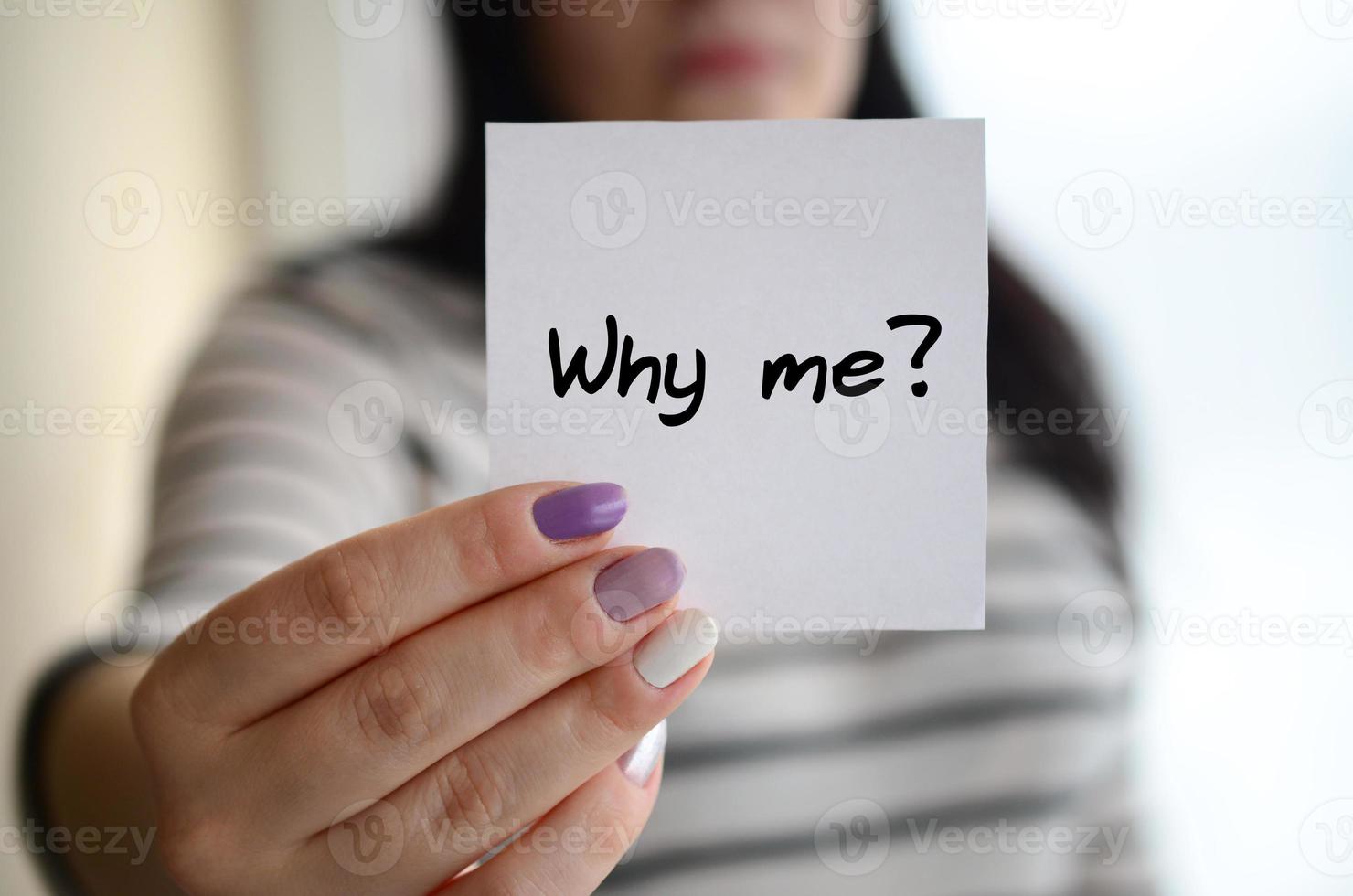 Young sad girl shows a white sticker. Caucasian brunette holding a sheet of paper with message. Why me photo