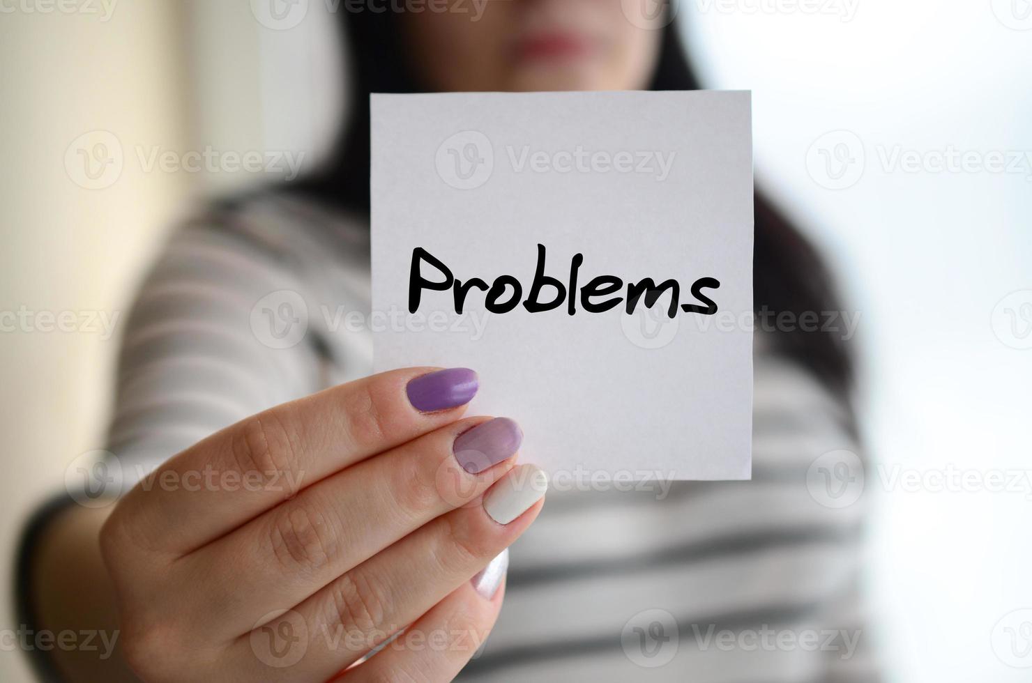 Young sad girl shows a white sticker. Caucasian brunette holding a sheet of paper with message. Problems photo