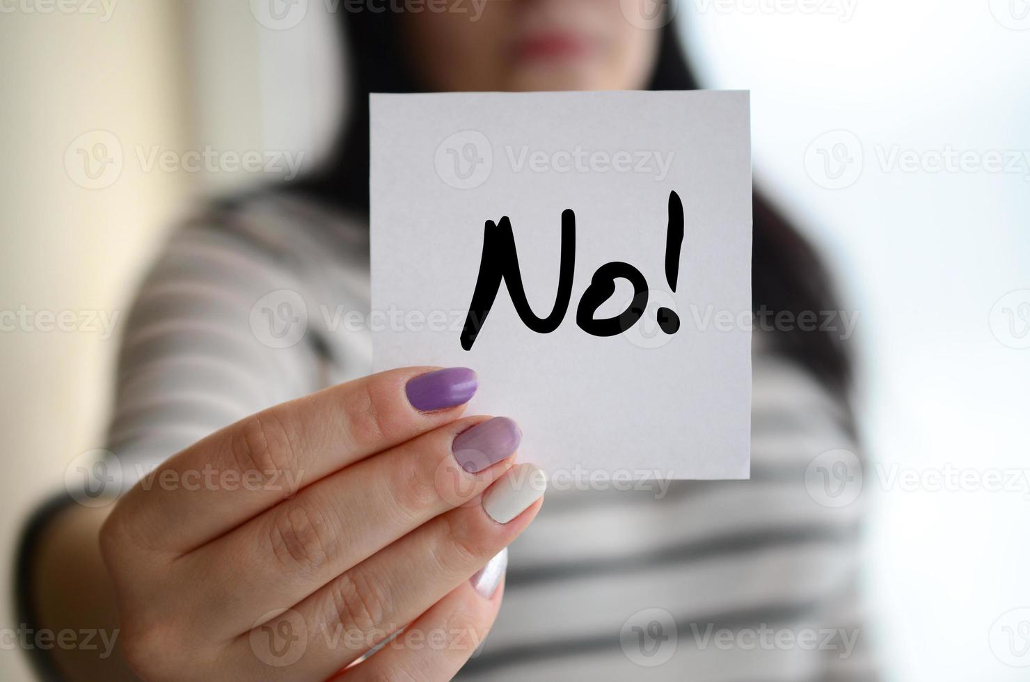 Young sad girl shows a white sticker. Caucasian brunette holding a sheet of paper with message. No photo