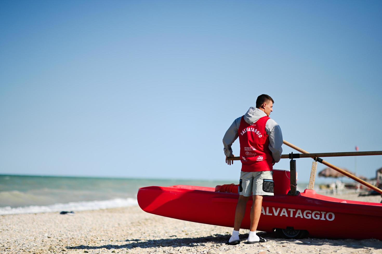 Red lifeguard rescue boat with man in italian beach. photo