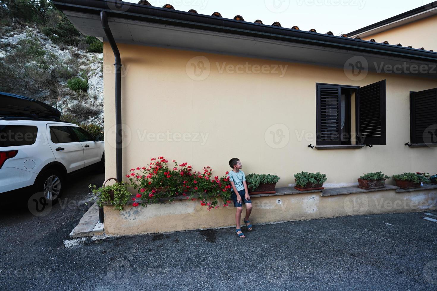 niño sentado cerca de la casa en nocera umbra, ciudad y comuna en la provincia de perugia, italia. foto