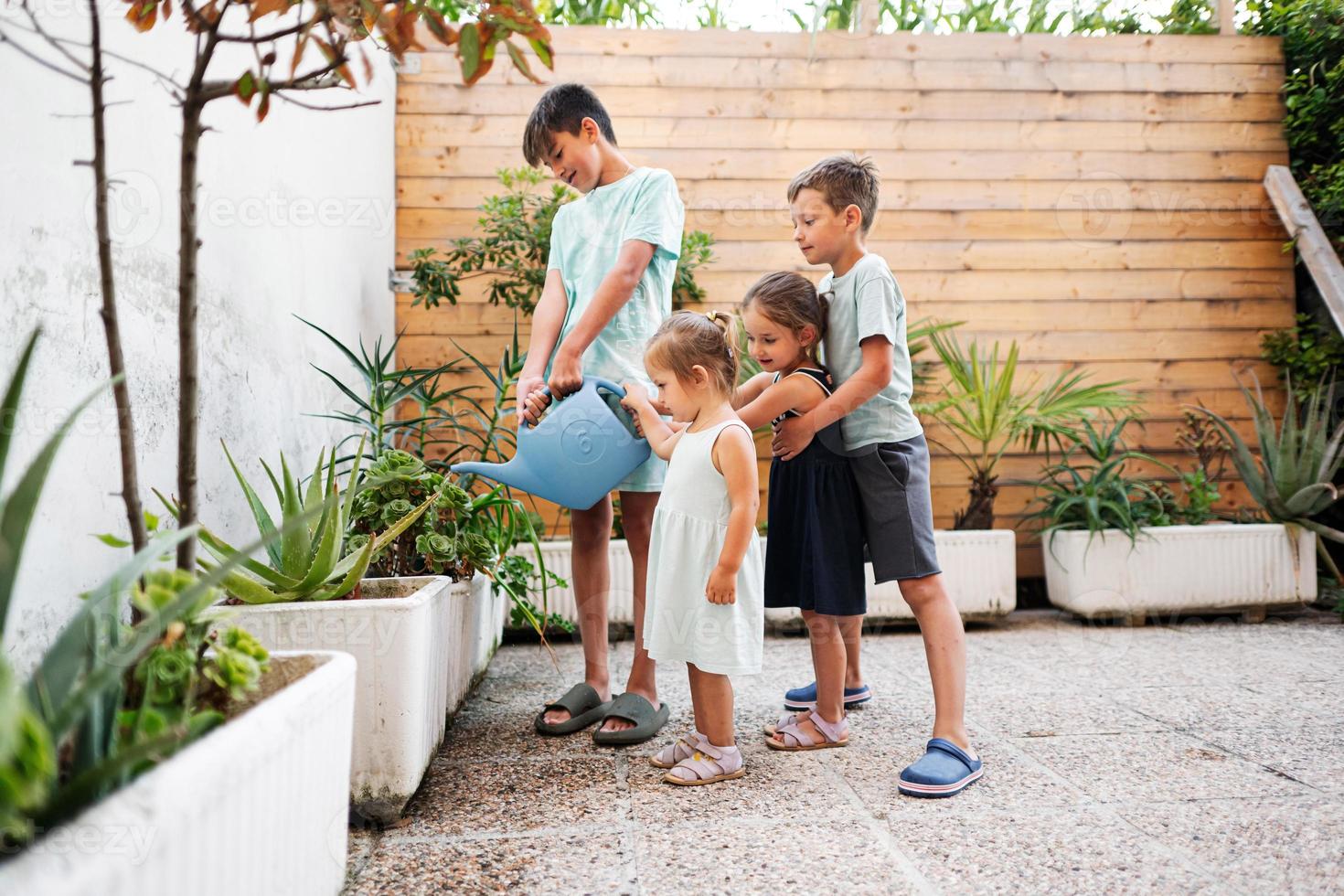 Children with can watering the flowers on the terrace of the house. photo