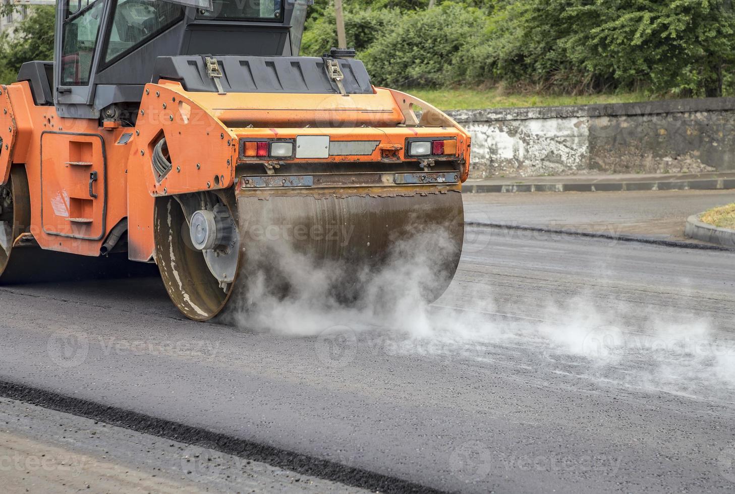 New asphalt road. the road roller working on the new road with smoke. Close photo