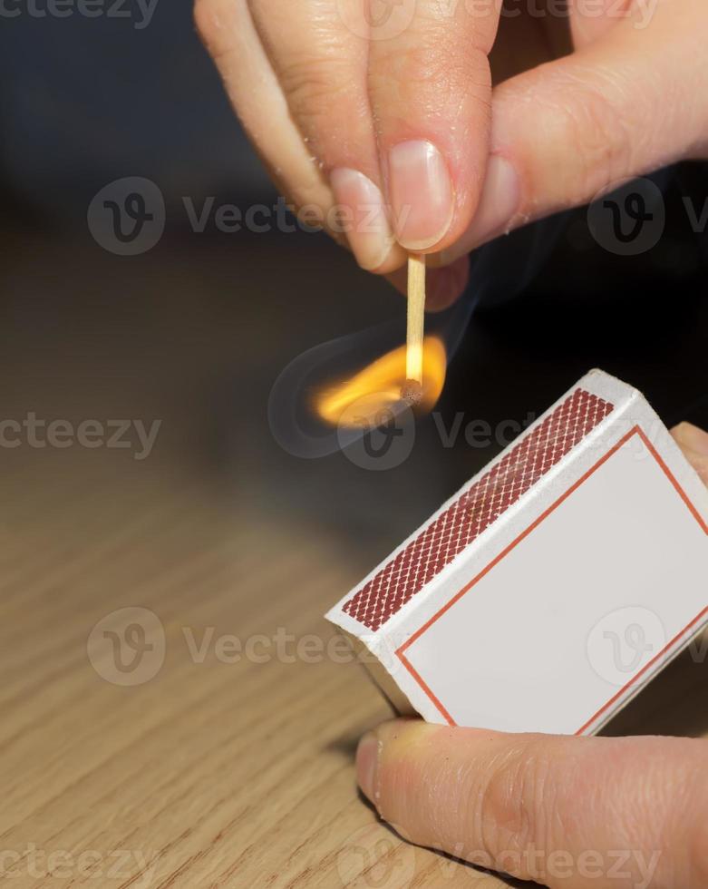 To light a match. The woman lights a match fire from a box of matches photo