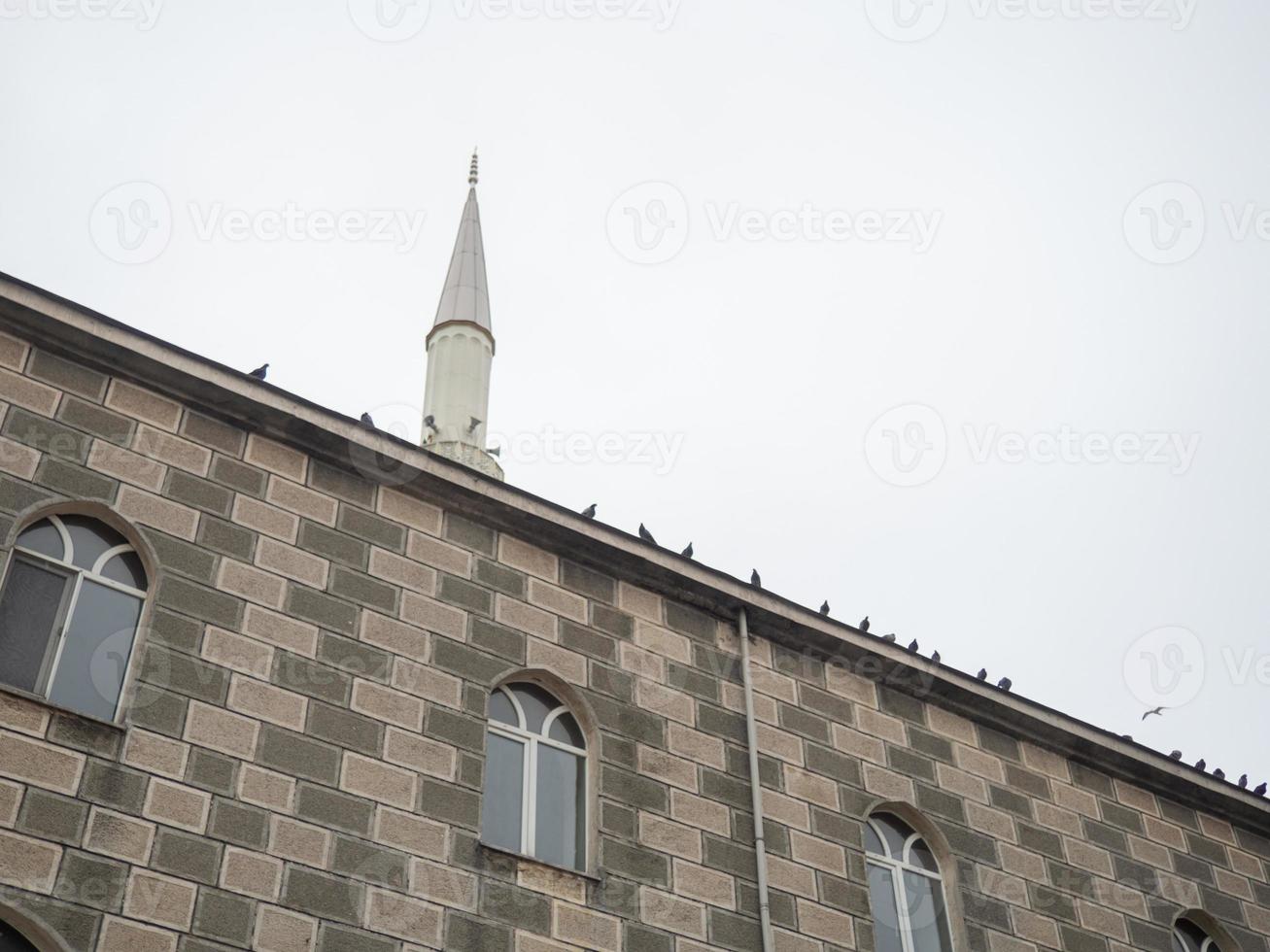Mosque wall with doves. The birds are sitting on the wall. Minaret photo