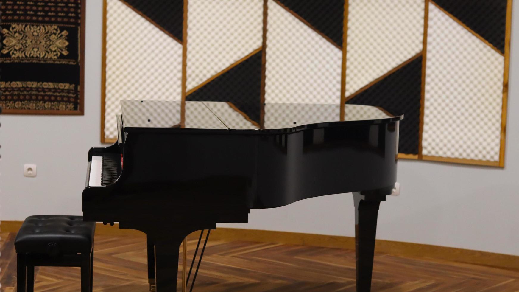 Photo of a classical piano with a batik oranamen recital room background