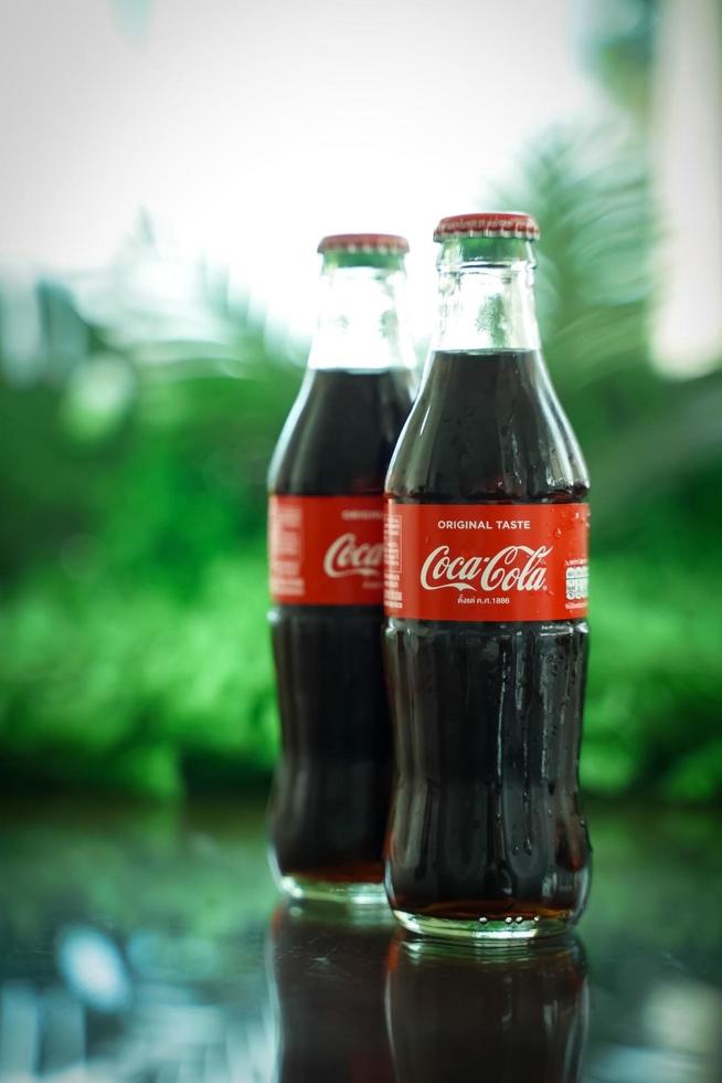 Ayutthaya, Thailand-25June2020- Coca-Cola Classic in a glass bottle and can on dark toned cement Background. Coca Cola, Coke is the most popular carbonated soft drink beverages sold around the world photo