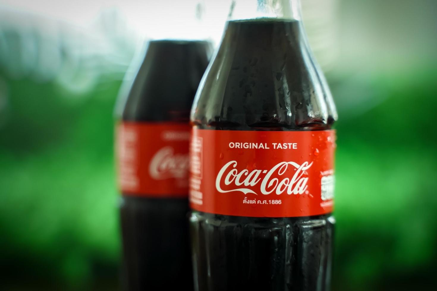 Ayutthaya, Thailand-25June2020- Coca-Cola Classic in a glass bottle and can on dark toned cement Background. Coca Cola, Coke is the most popular carbonated soft drink beverages sold around the world photo