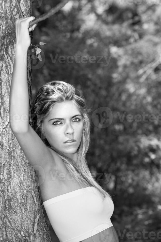 Portrait in black and white style movie star Beautiful blonde woman with intense eyes resting on a plant photo