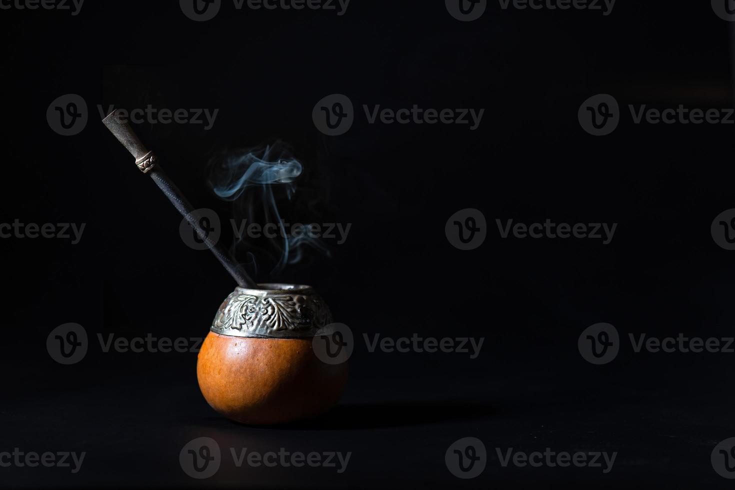 Yerba hot tea mate drink with smoke on black background photo
