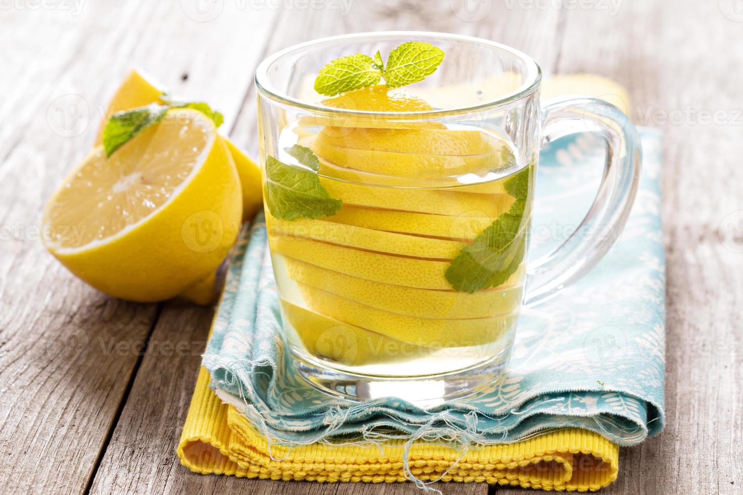 Tea with mint and whole lemon in a transparent cup photo