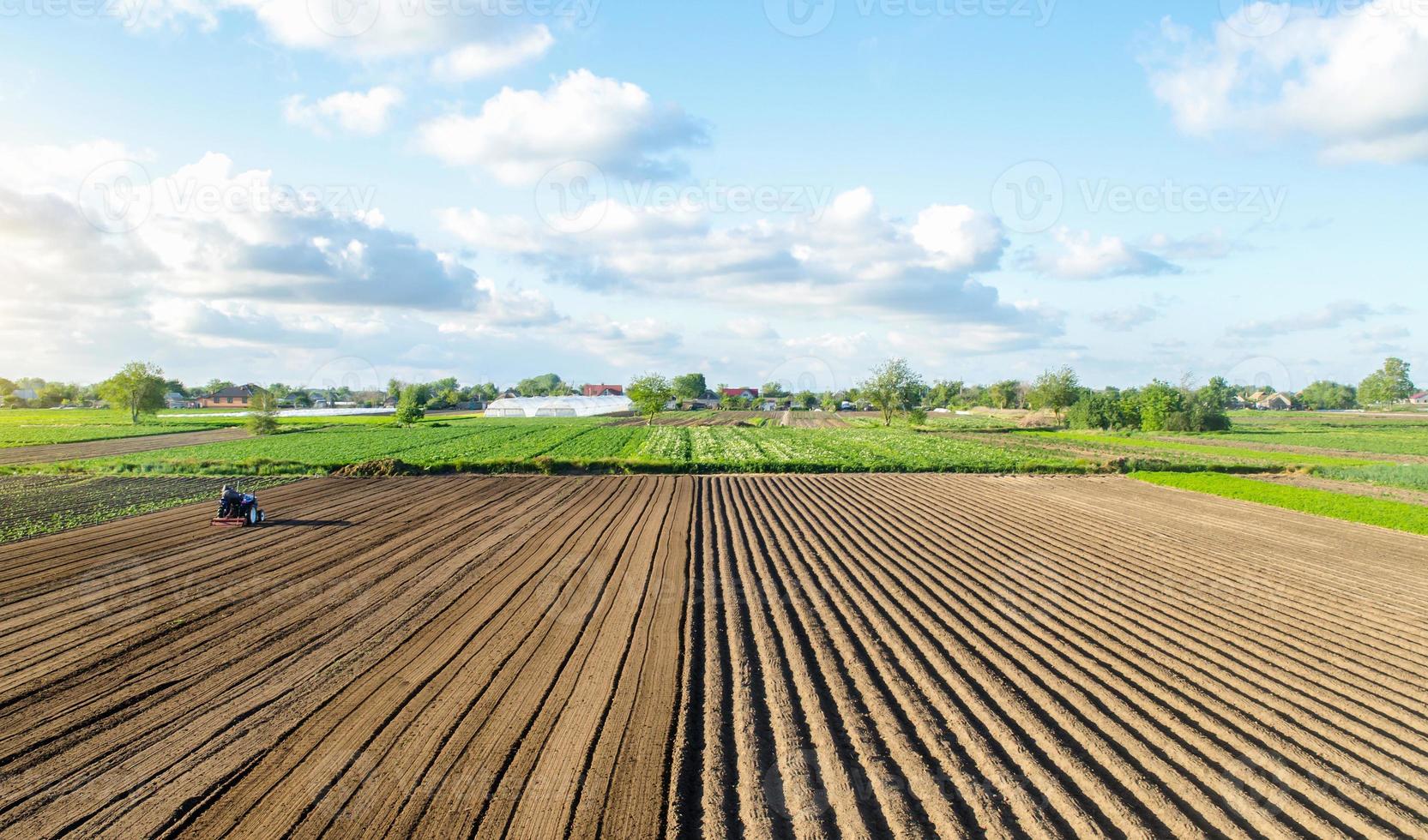 Farm field landscape and a tractor. Agricultural industry. Development