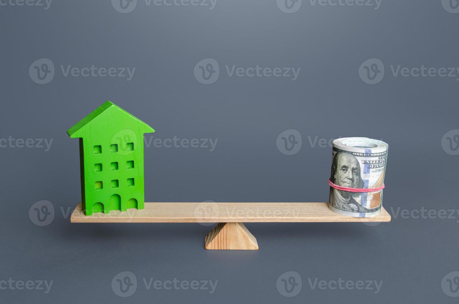 Green house and money on the scales. Evaluation of savings on energy and utilities in an efficient eco building. Building maintenance. Renovation improvement of old buildings. Profitability photo