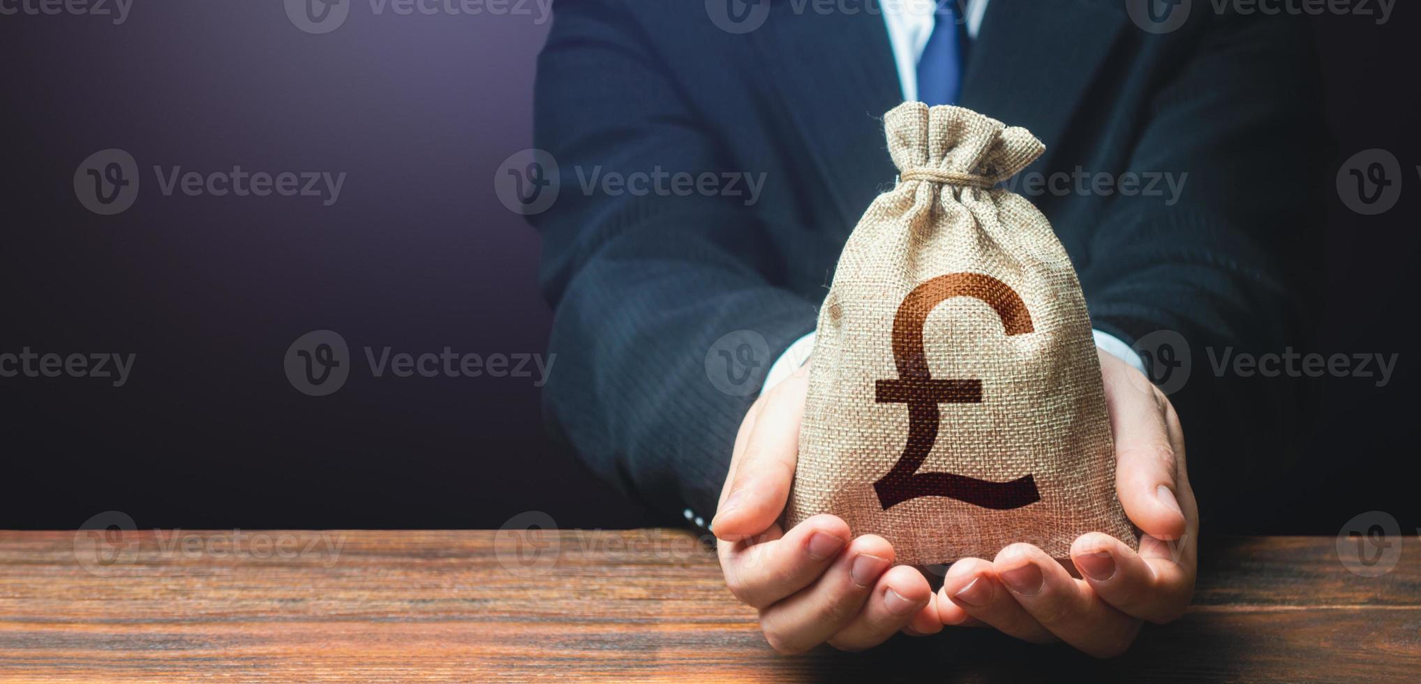 Businessman holds out british pound sterling money bag. Getting a grant. Mortgage, loan approval. Salary, benefits, profit. Attracting investments. Deposit savings. Banking and crediting. Easy Money. photo