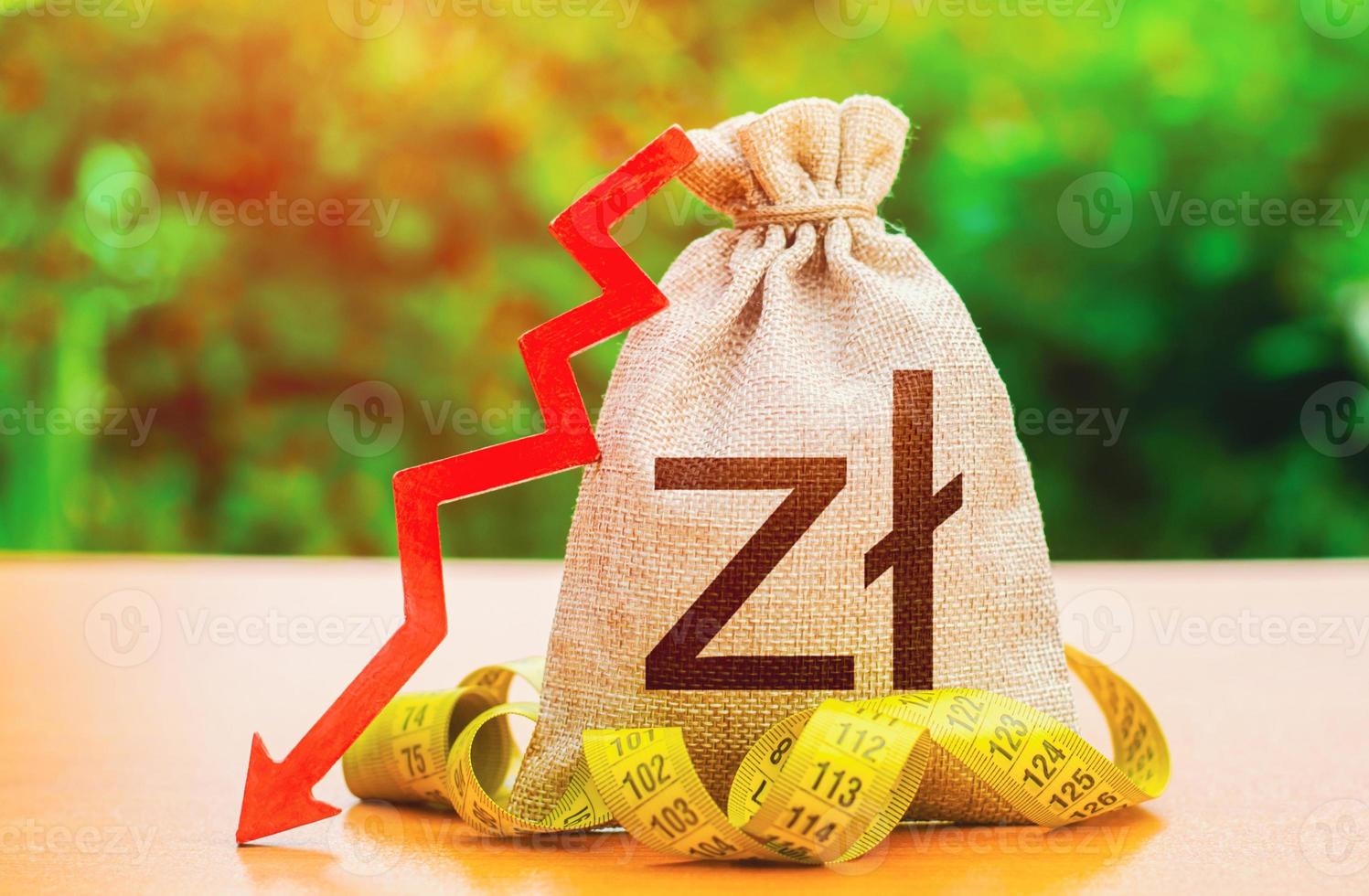 Polish zloty money bag with down arrow and measure tape. Reduced wages, cuts in social benefits. Falling wages and welfare. Cutting costs. Capital outflow. Decrease in discount rate by national bank. photo