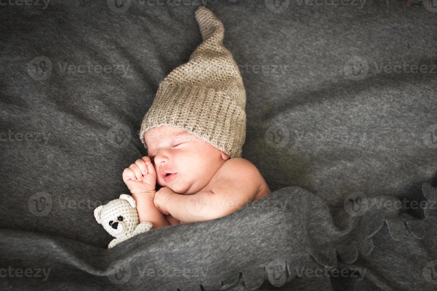 bebé recién nacido durmiendo con un juguete al lado del oso de peluche de punto foto