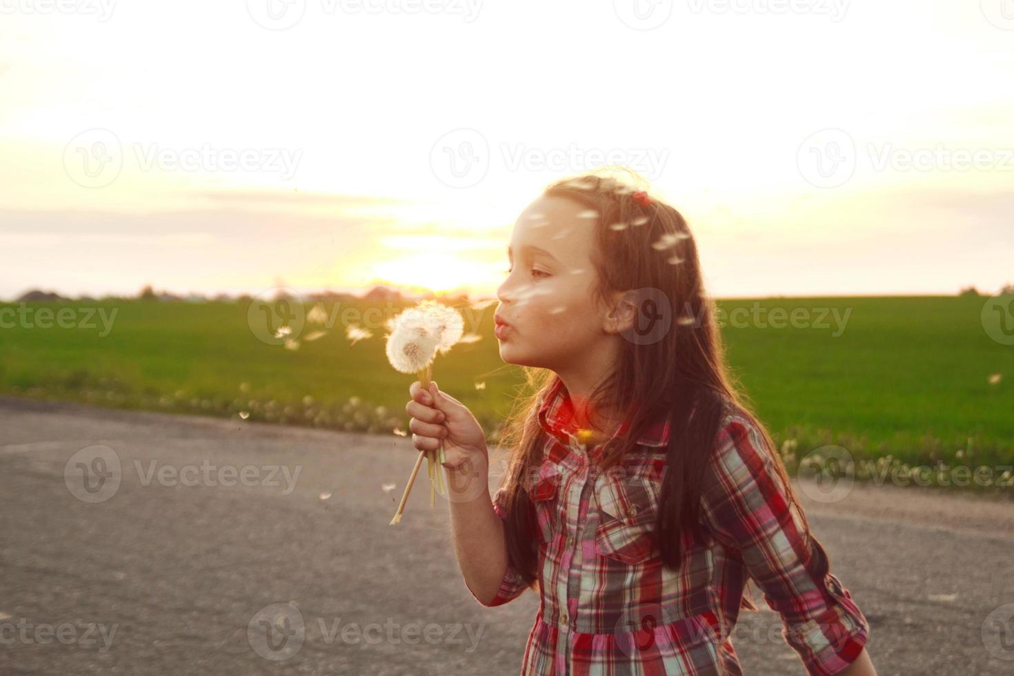 girl blows on a dandelion photo