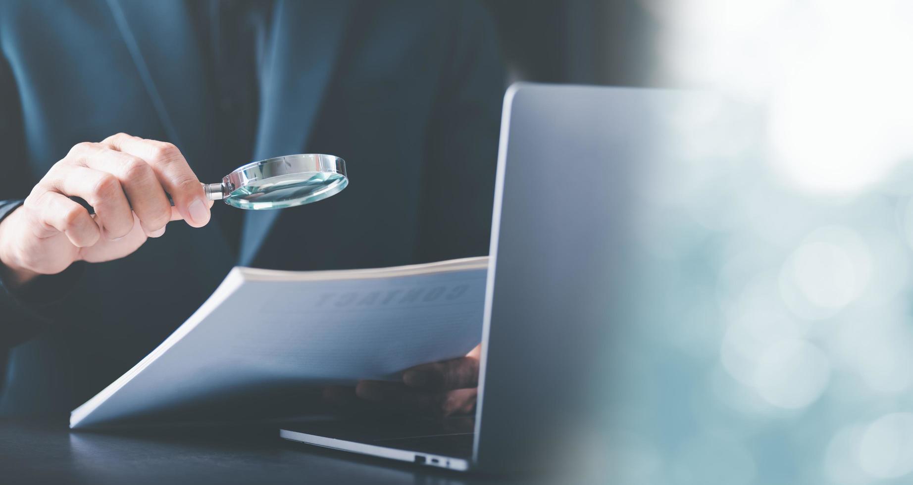 Businessman holding a magnifying glass,Audit Document Concepts, quality assessment management With a checklist, business document evaluation process, market data report analysis and consulting photo