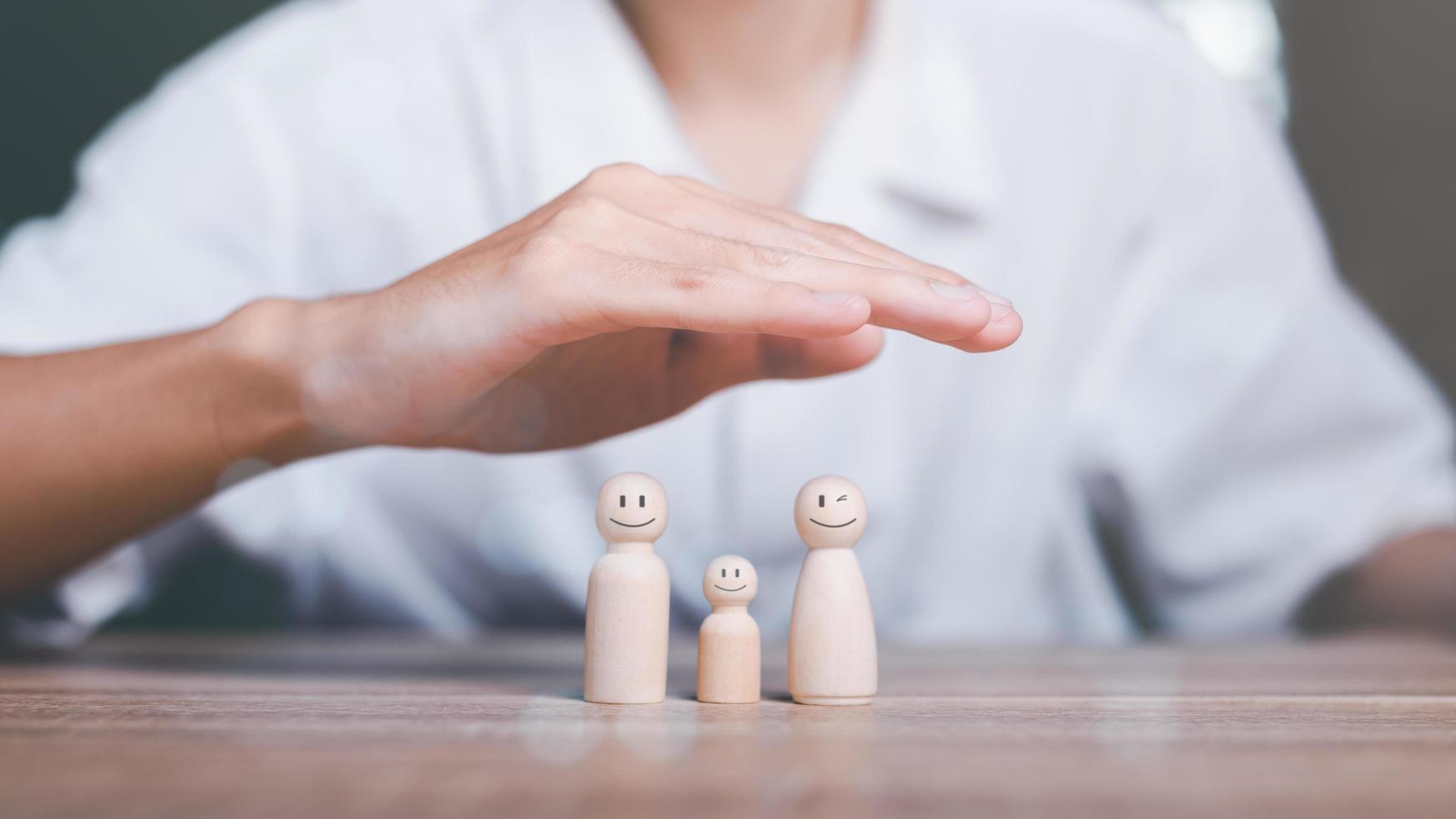 Man's hand on a wooden doll Refers to the protection and protection of safety ,concept of insurance management planning To ensure both health and financial safety,Property and Family Risk Reduction photo