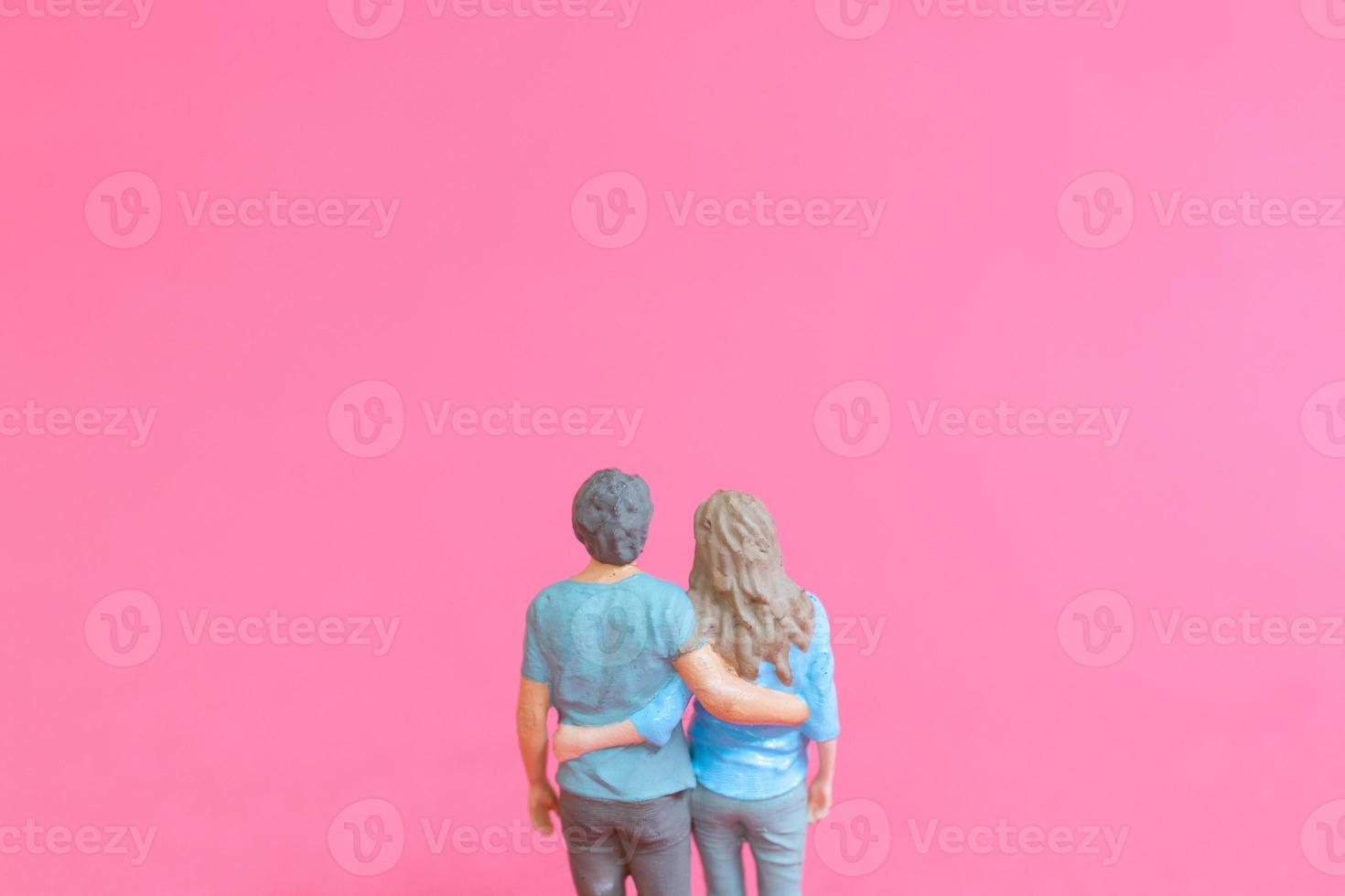 Miniature people man and woman in casual cloth standing together on pink background photo
