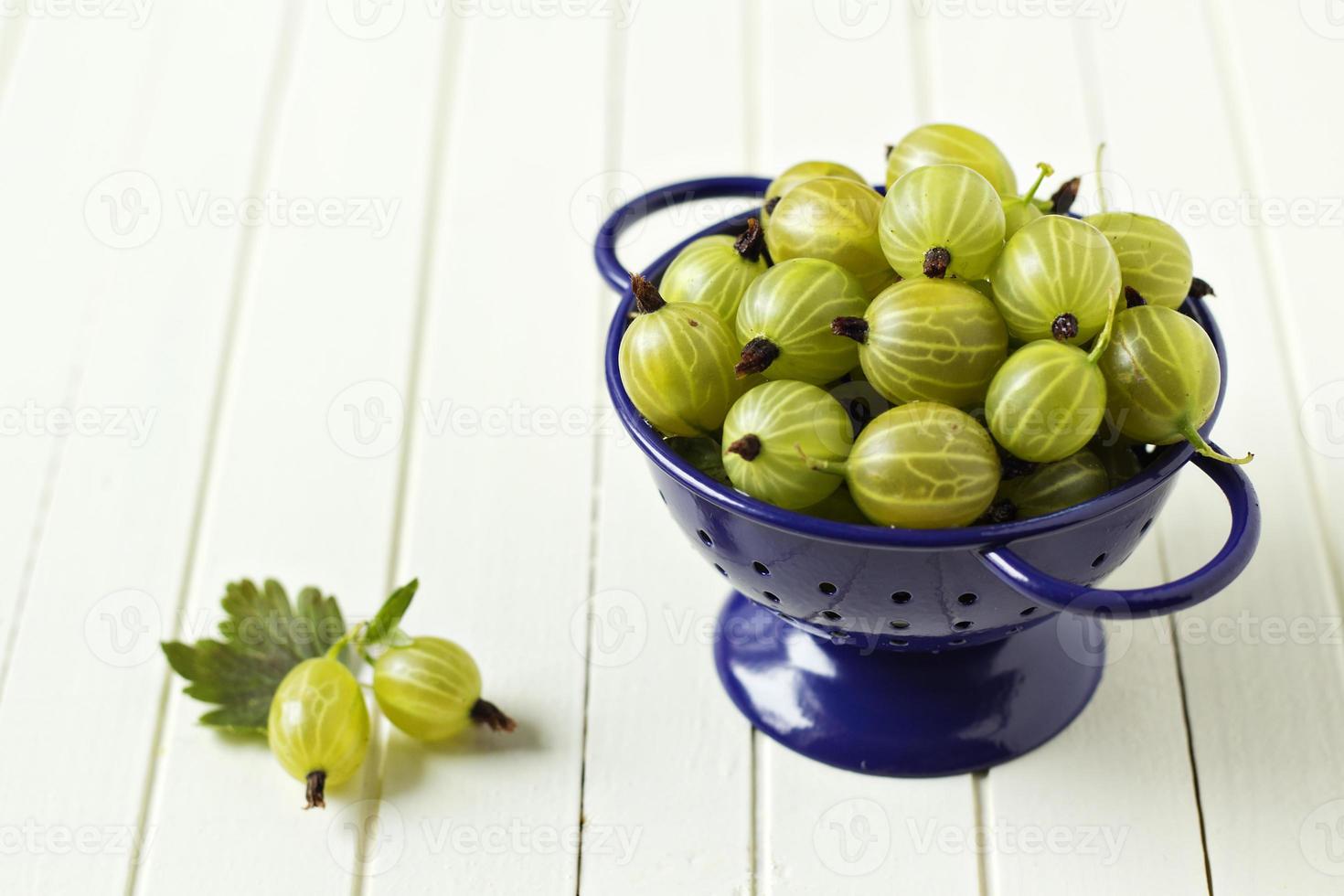 Fresh gooseberries in blue colander, summer berries photo