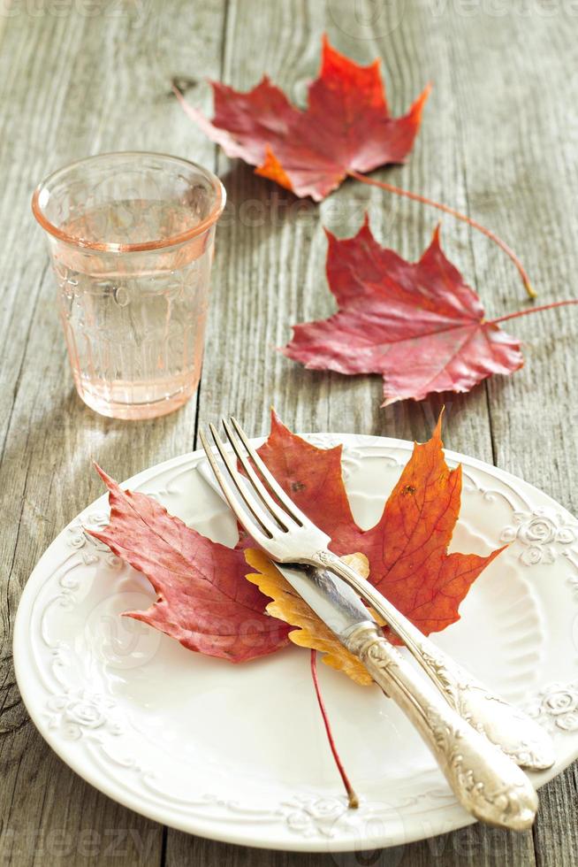 Autumn table setting with fall leaves, fork and knife photo