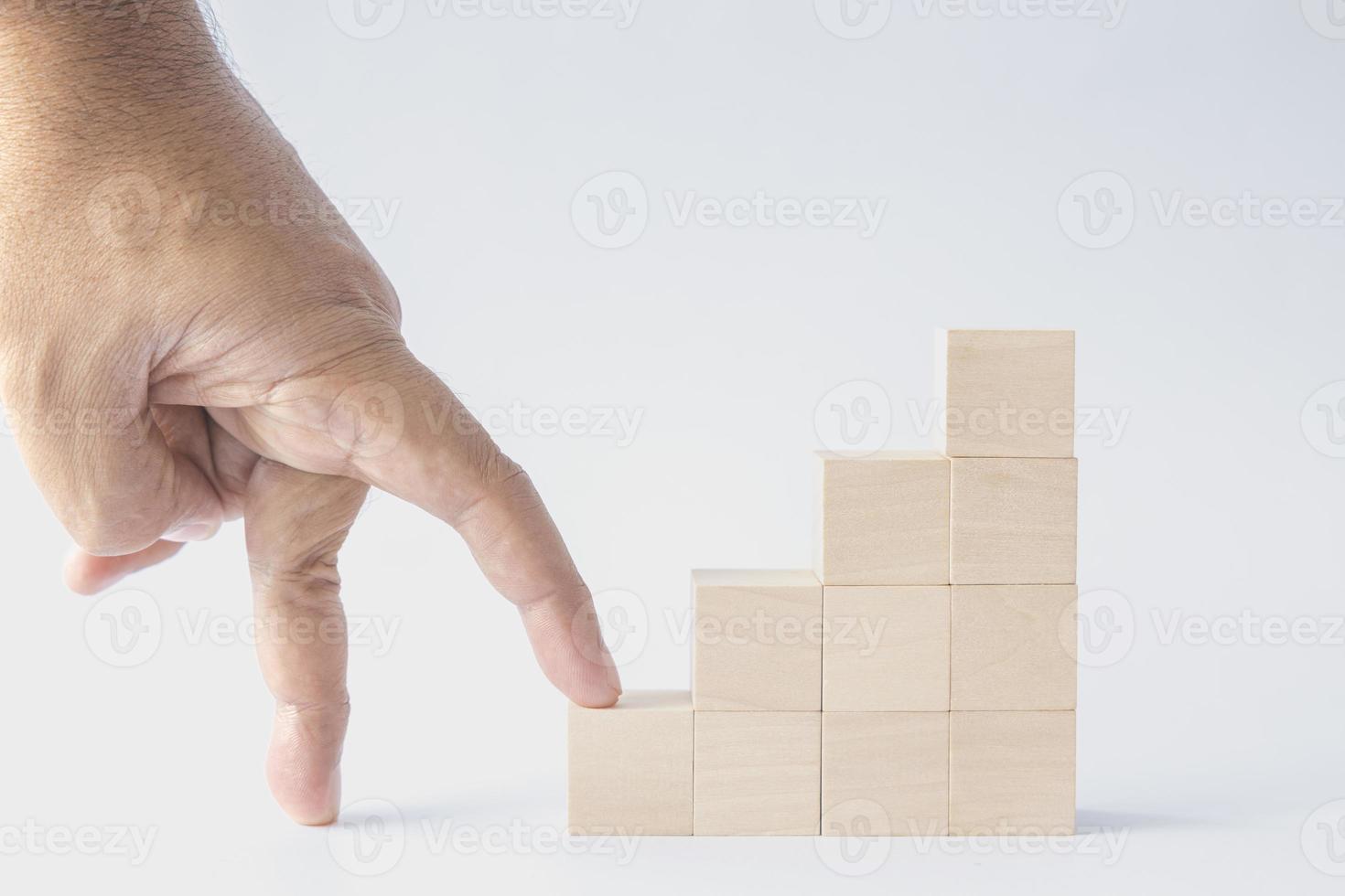 Fingers are going up stacked wooden cubes as steps on white background. concept about education, business, play, strategy, and success. photo