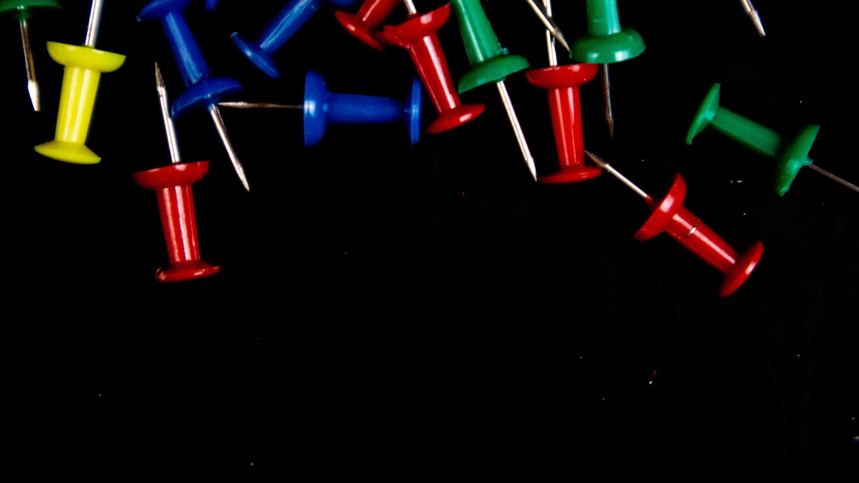 multicolored thumbtacks on a black background photo