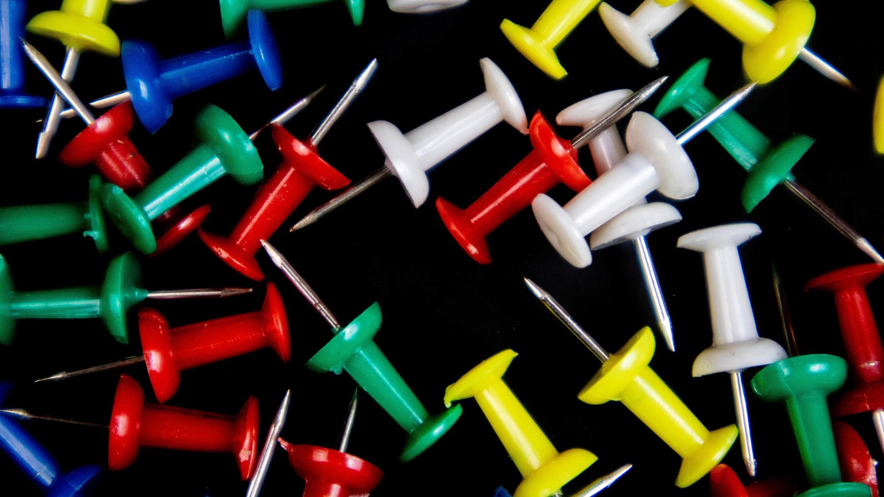 multicolored thumbtacks on a black background photo