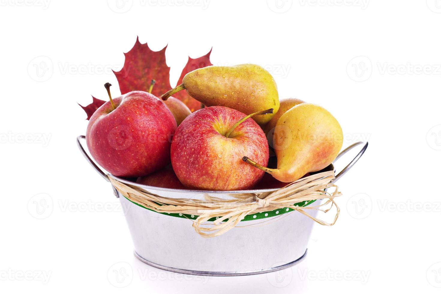 manzanas y peras en cubo de metal con hoja de otoño foto