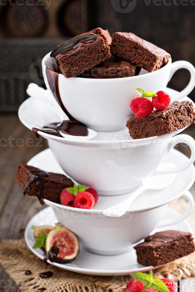 brownies en tazas de café apiladas con salsa de chocolate foto