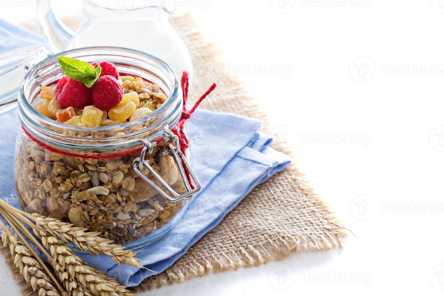 Homemade citrus granola in a glass jar on white photo