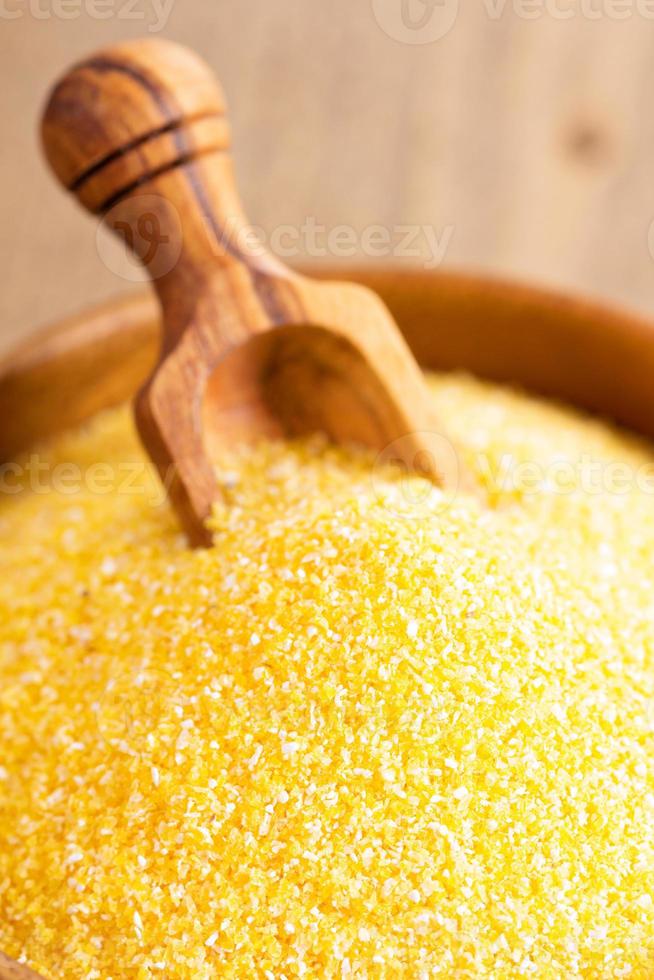 Dry raw cornmeal in wooden bowl photo