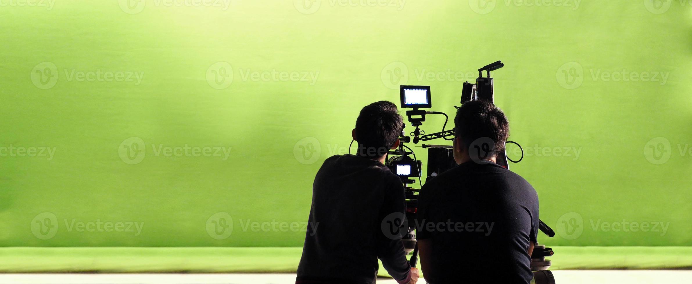 Camera and green screen studio in panorama view and man working or shooting or recording or filming. photo